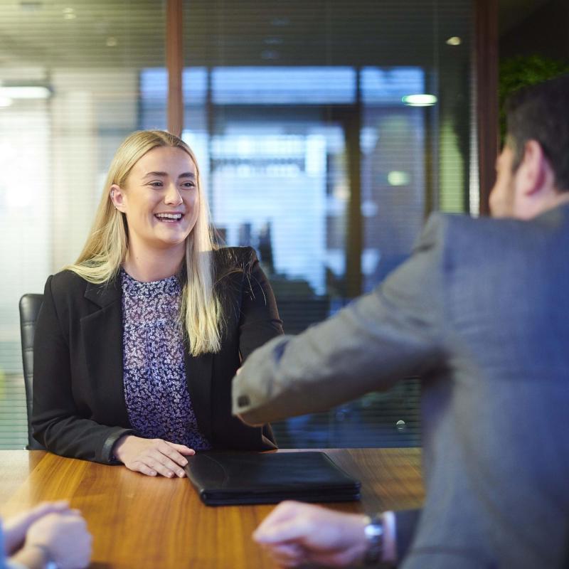 Smiling interviewee shaking hands with interviewer